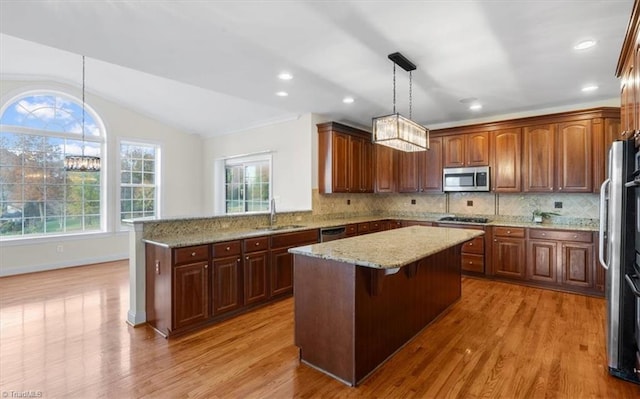 kitchen with sink, a center island, vaulted ceiling, and appliances with stainless steel finishes