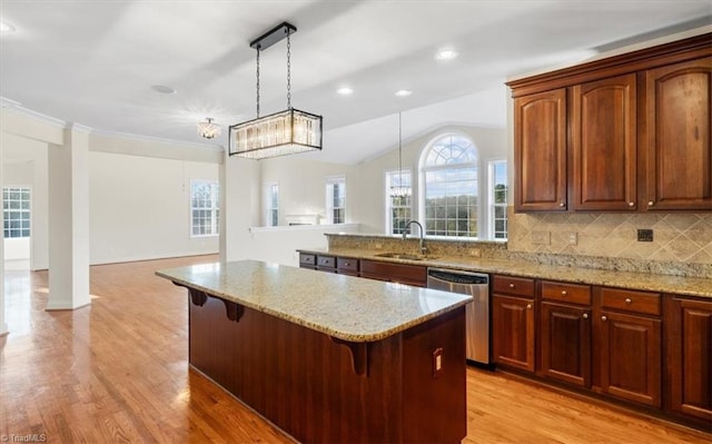 kitchen featuring pendant lighting, a breakfast bar, sink, stainless steel dishwasher, and light hardwood / wood-style floors