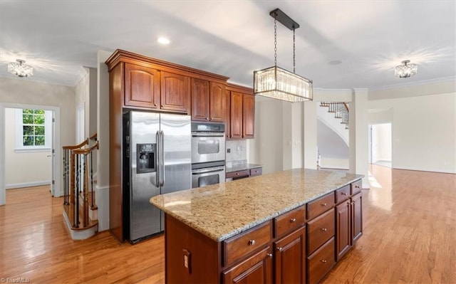 kitchen with decorative light fixtures, light hardwood / wood-style floors, crown molding, and stainless steel appliances