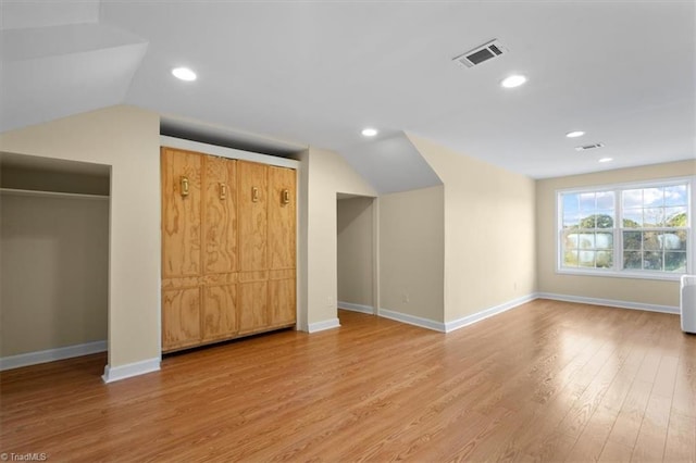 additional living space with hardwood / wood-style flooring and vaulted ceiling