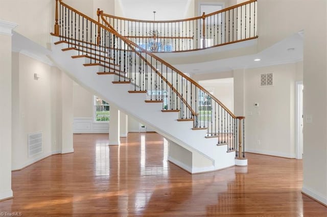 stairway with hardwood / wood-style flooring, crown molding, and a high ceiling