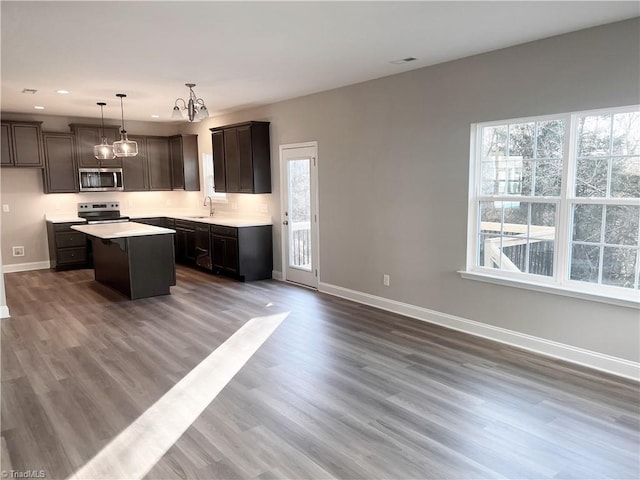 kitchen featuring an inviting chandelier, baseboards, appliances with stainless steel finishes, and a sink