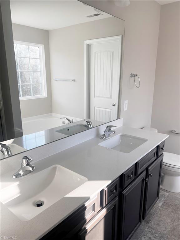 bathroom featuring a tub to relax in, vanity, and toilet