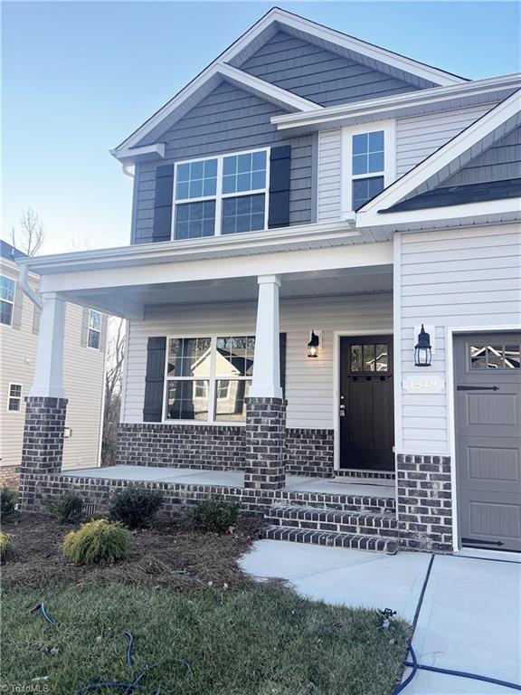 property entrance featuring a porch, brick siding, and a garage