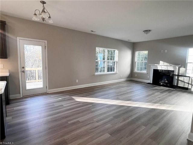 unfurnished living room featuring a chandelier and dark hardwood / wood-style floors