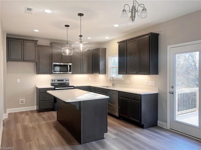 kitchen featuring visible vents, light wood-style flooring, a sink, appliances with stainless steel finishes, and an inviting chandelier