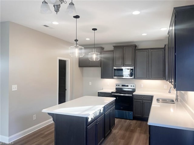 kitchen with appliances with stainless steel finishes, sink, pendant lighting, dark hardwood / wood-style floors, and a kitchen island