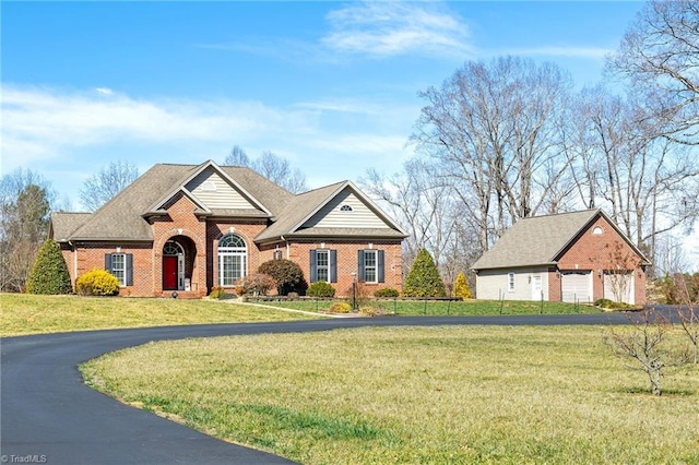 view of front of property featuring a front yard, an outdoor structure, a detached garage, and brick siding