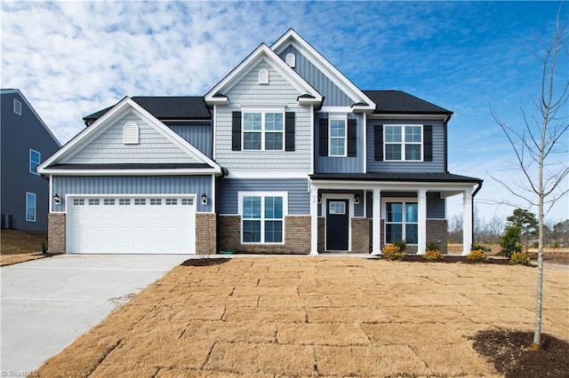 craftsman house with driveway, a porch, board and batten siding, an attached garage, and brick siding