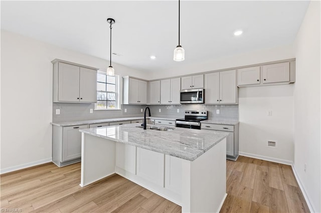 kitchen featuring baseboards, light wood finished floors, a sink, stainless steel appliances, and backsplash