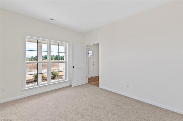 carpeted spare room featuring visible vents and baseboards