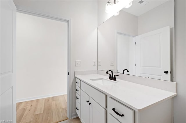 bathroom with visible vents, vanity, baseboards, and wood finished floors