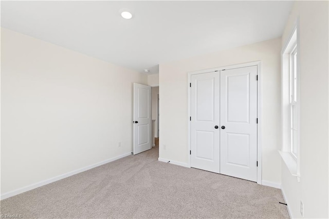 unfurnished bedroom with a closet, recessed lighting, baseboards, and carpet floors