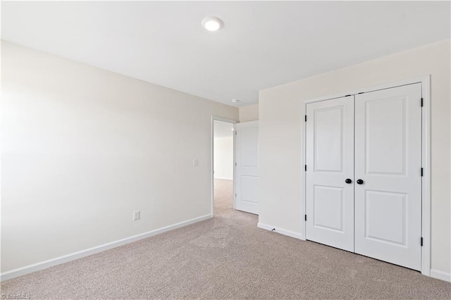 unfurnished bedroom with a closet, carpet flooring, and baseboards