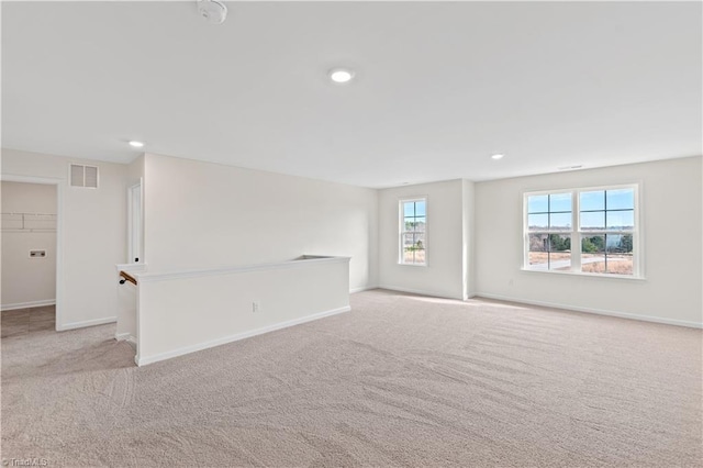 unfurnished room featuring light colored carpet, visible vents, and baseboards