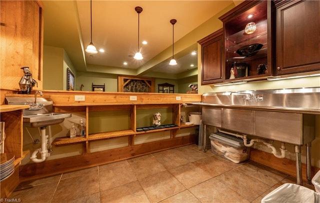 interior space with light tile patterned flooring, decorative light fixtures, and stainless steel counters