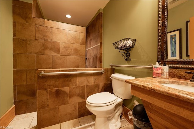 bathroom featuring a tile shower, tile walls, tile patterned flooring, vanity, and toilet