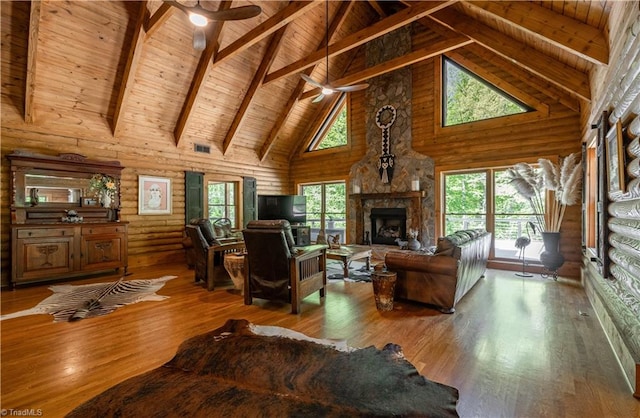 living room with ceiling fan, beamed ceiling, wood-type flooring, high vaulted ceiling, and a fireplace