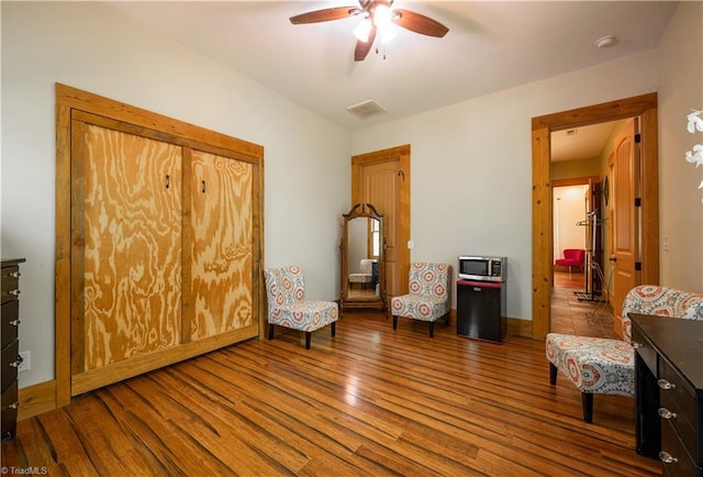 sitting room with ceiling fan and hardwood / wood-style flooring