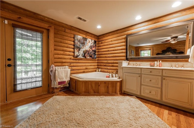 bathroom featuring log walls, hardwood / wood-style floors, and a bathing tub