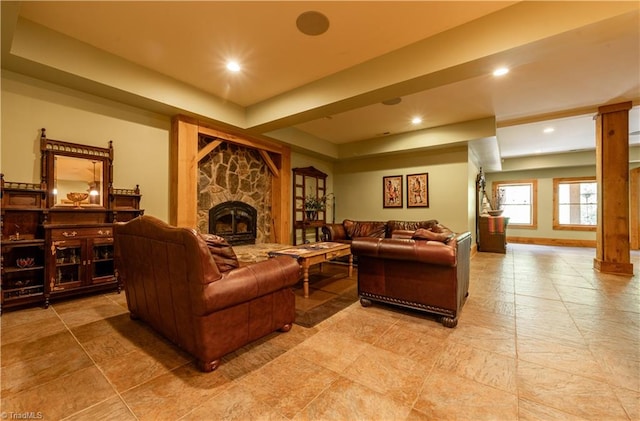 living room featuring decorative columns and a stone fireplace