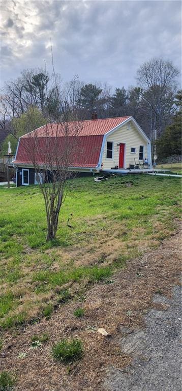 view of front of house with a gambrel roof, a front yard, and metal roof