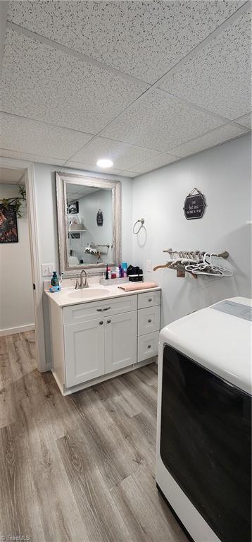 bathroom with wood finished floors, vanity, washer / clothes dryer, a paneled ceiling, and recessed lighting