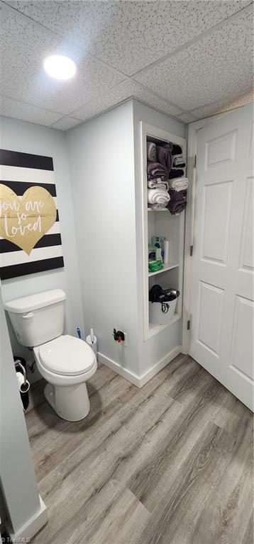 bathroom featuring toilet, wood finished floors, and a paneled ceiling
