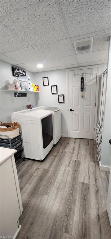 clothes washing area with washing machine and clothes dryer, light wood-style floors, and laundry area