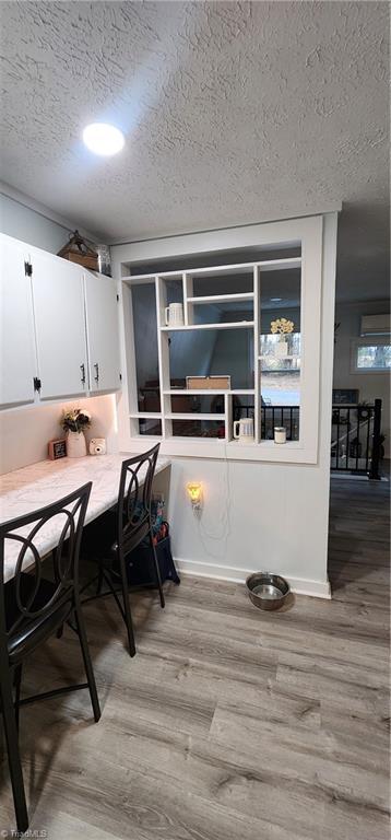 dining area with baseboards, a textured ceiling, and light wood-style flooring