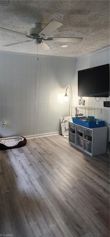 living room with wood finished floors, baseboards, and ceiling fan