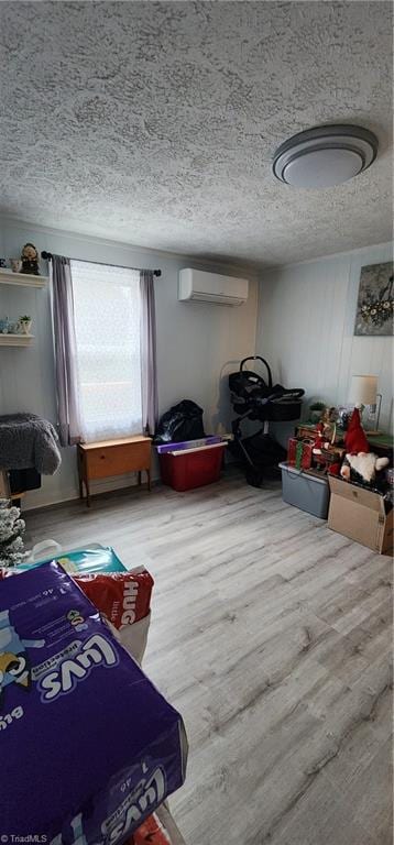 bedroom featuring wood finished floors, a textured ceiling, and a wall mounted air conditioner