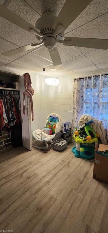 interior space featuring wood finished floors, a closet, a ceiling fan, and a drop ceiling