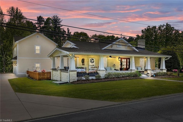view of front facade with ceiling fan, covered porch, a chimney, a lawn, and driveway