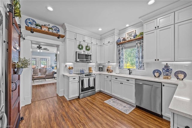 kitchen with dark wood-style flooring, ceiling fan, white cabinets, a sink, and appliances with stainless steel finishes