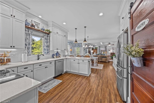 kitchen featuring appliances with stainless steel finishes, white cabinets, a peninsula, and dark wood-style floors