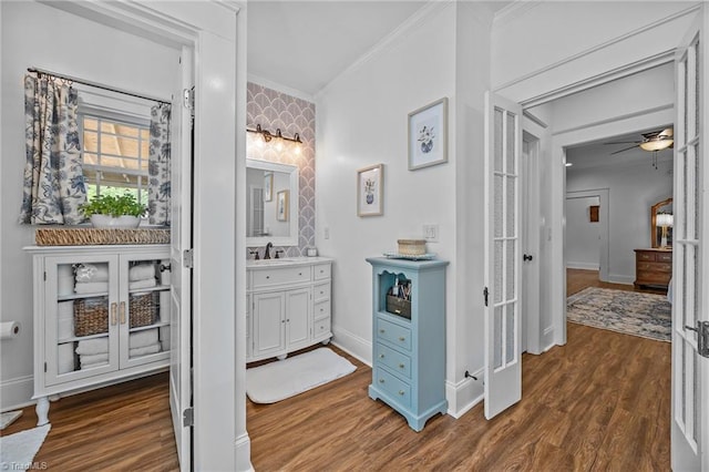 bathroom featuring vanity, ornamental molding, wood finished floors, baseboards, and ceiling fan