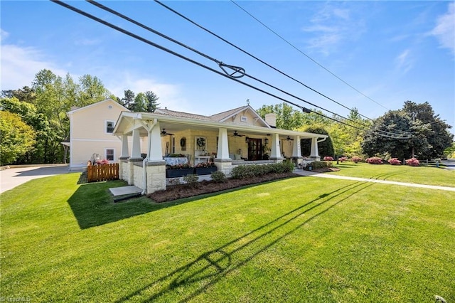 back of property with a ceiling fan, a yard, and covered porch