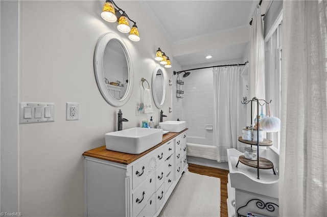 bathroom with a sink, ornamental molding, double vanity, and wood finished floors