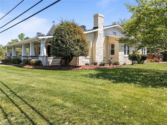 view of side of property with a chimney, a yard, and stone siding
