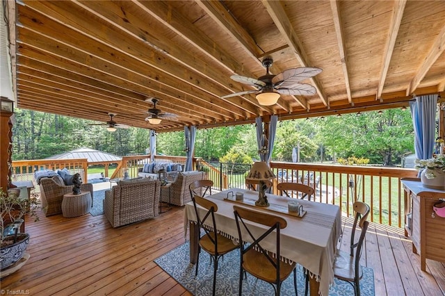 wooden deck with outdoor lounge area, a ceiling fan, and outdoor dining area