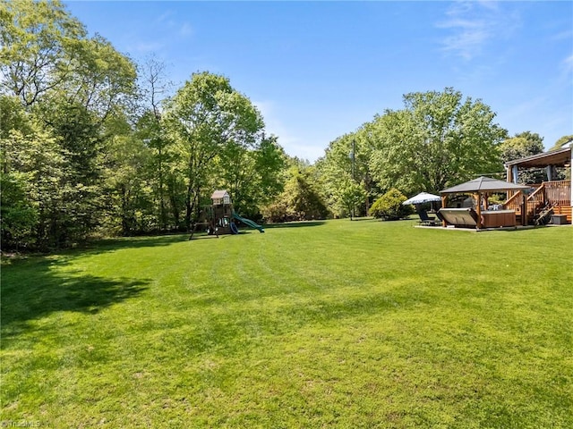view of yard with a hot tub, a gazebo, and a playground