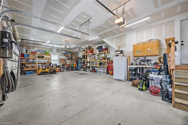 garage featuring freestanding refrigerator, a garage door opener, and a workshop area