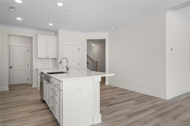 kitchen with an island with sink, light hardwood / wood-style flooring, white cabinetry, and decorative backsplash