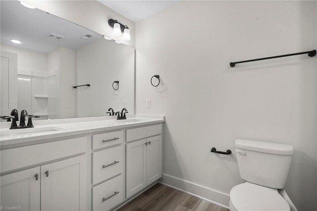 bathroom featuring wood-type flooring, double sink vanity, and toilet