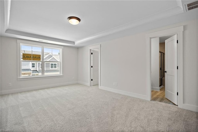 carpeted empty room with a tray ceiling