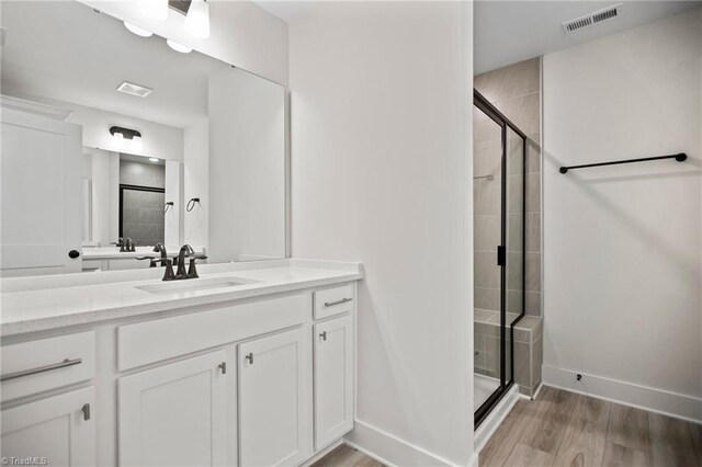 bathroom featuring hardwood / wood-style floors, a shower with shower door, and vanity