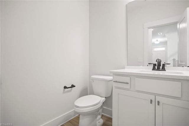 bathroom with hardwood / wood-style flooring, vanity, and toilet