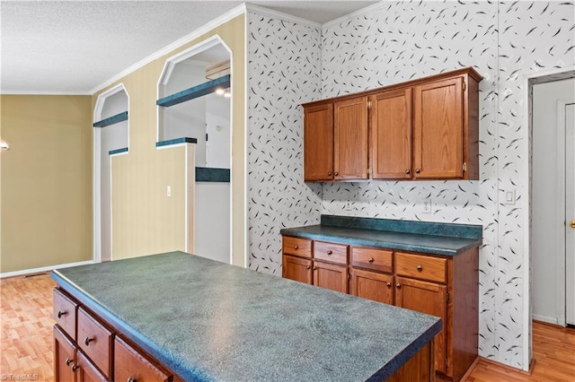 103 Forest Dr, King, NC 27021 - kitchen featuring ornamental molding, dark countertops, light wood-type flooring, brown cabinetry, and a kitchen island