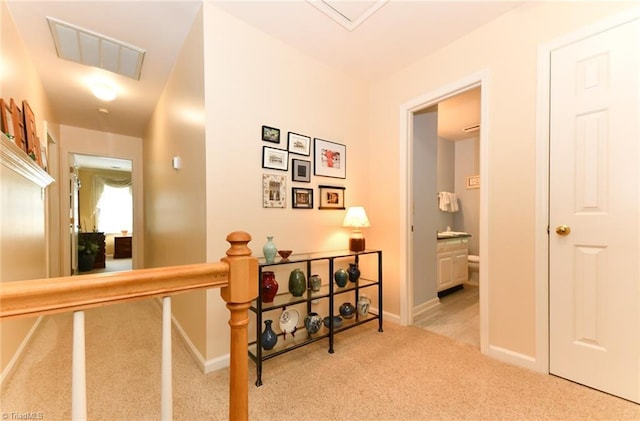 corridor featuring baseboards, an upstairs landing, carpet flooring, and visible vents